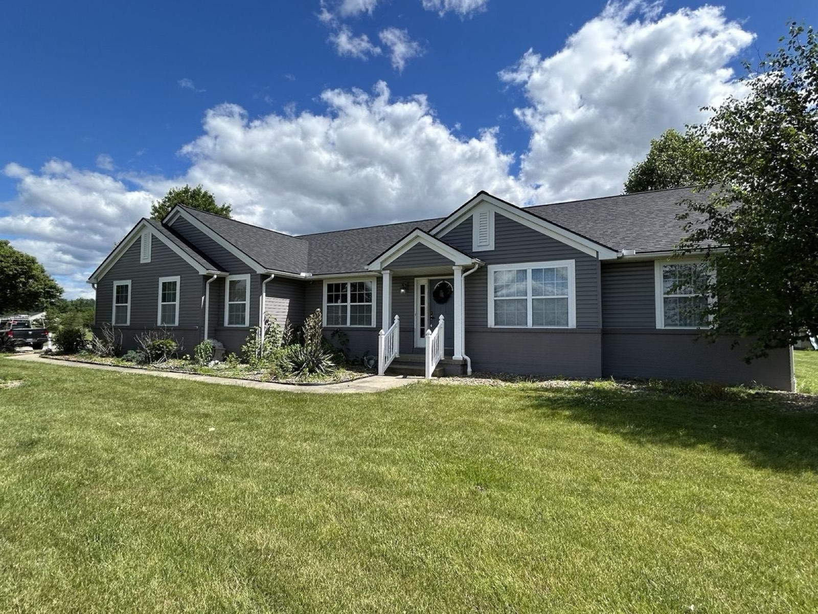 Gray ranch home with a new roof under a blue sky