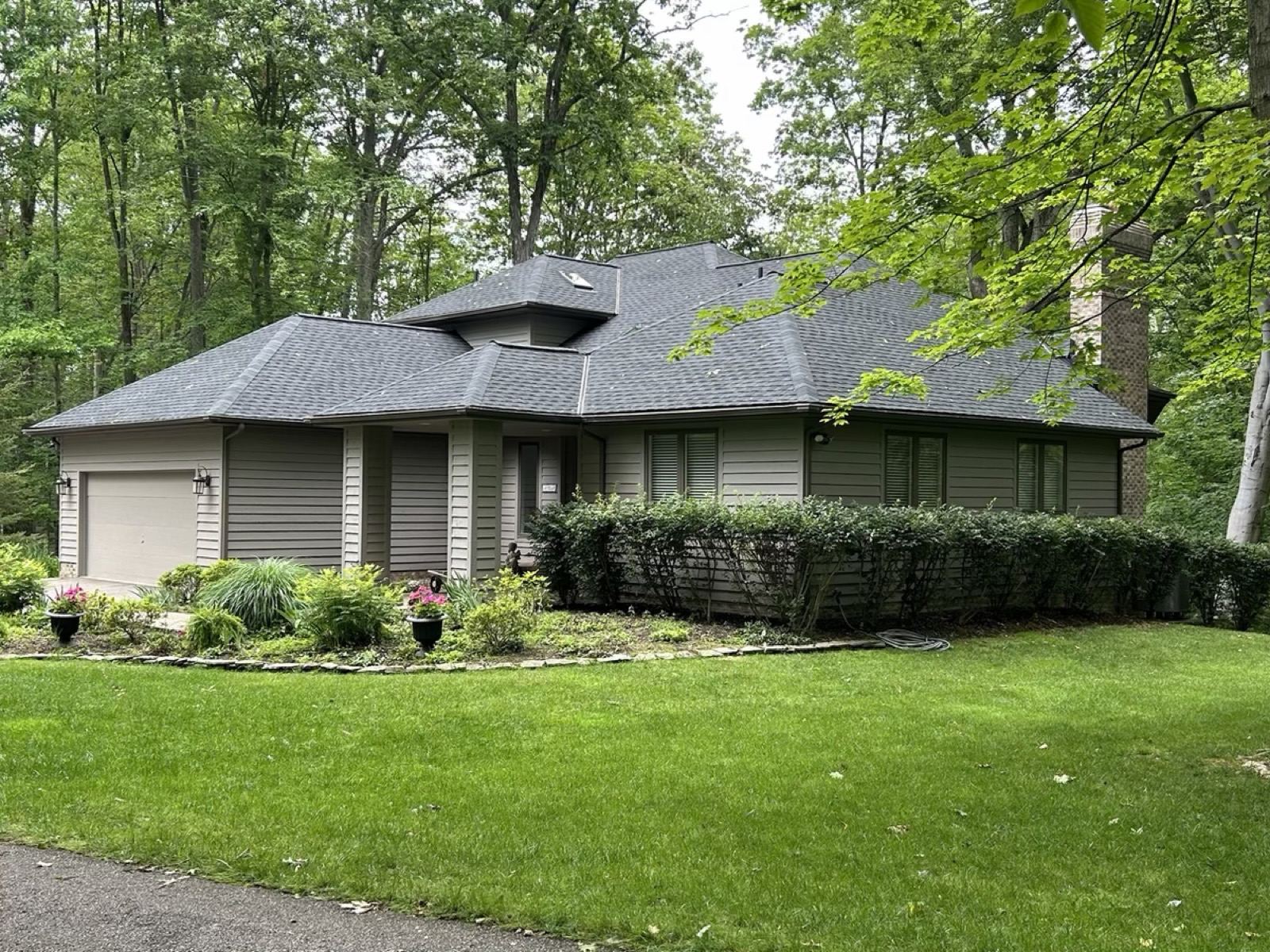 Tan home with a new hip roof and a garden out front