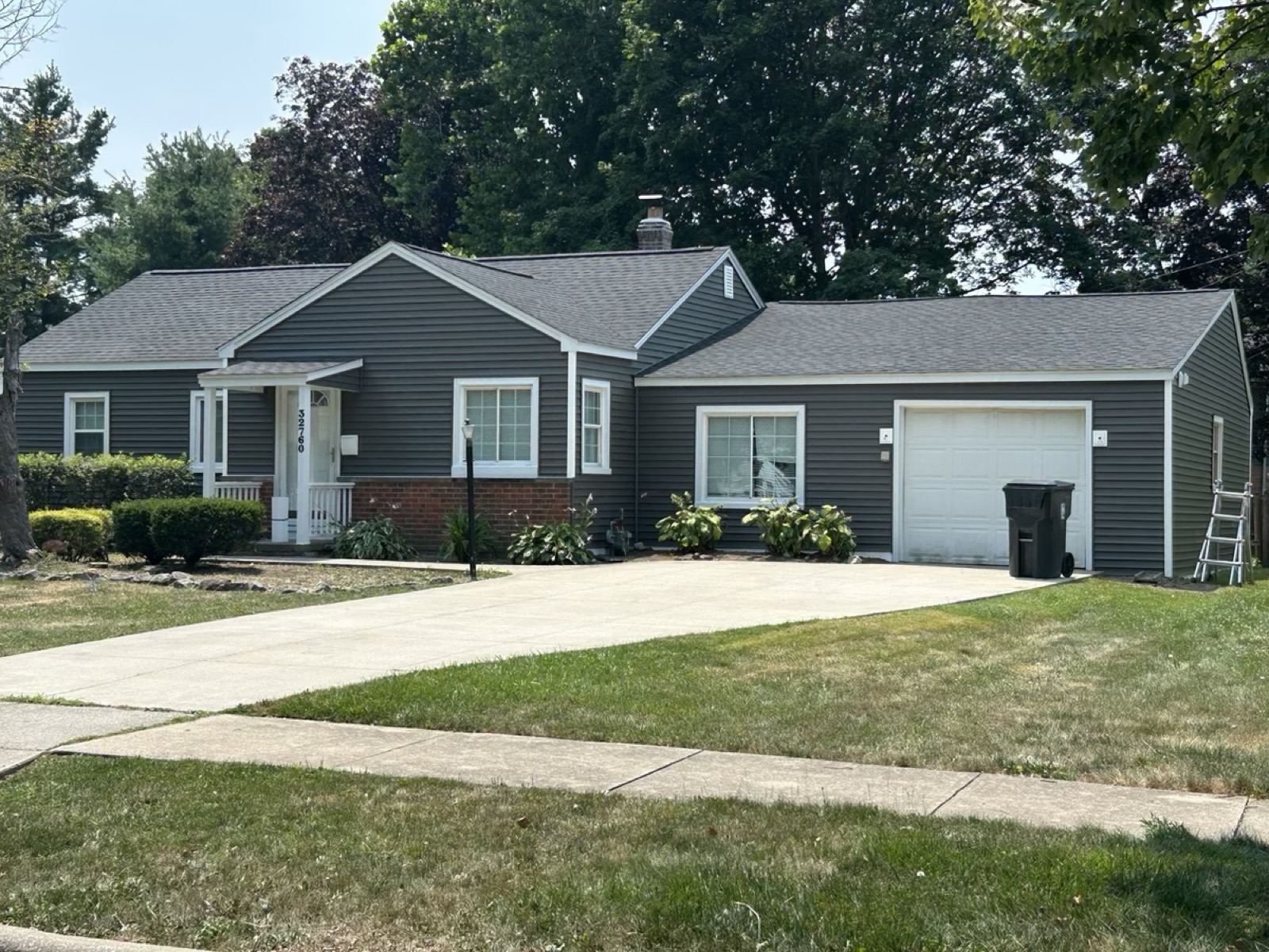 Gray ranch home with a new roof and a white garage door